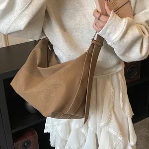 Detail of brown textured leather crossbody bag with wide shoulder strap and side zipper