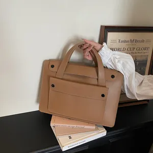 Brown leather work bag detail showing the sleek front pocket and comfortable double handles