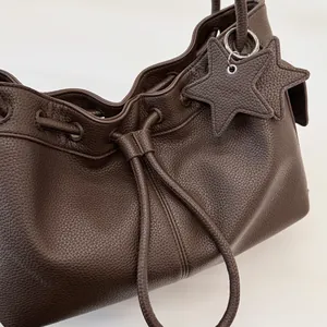Close-up of deep brown lychee grain leather texture and star-shaped bag charms