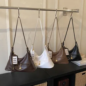 Detailed view of four retro PU leather underarm bags hanging on a metal rack