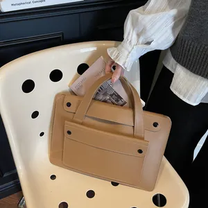 Detail of khaki leather business handbag with black button front pocket and sleek finish
