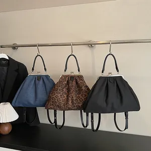 Chic cloud-shaped tote bags in leopard, denim, and black hanging on a metal rack