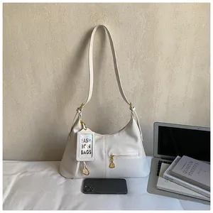 Detail view of cream white hobo shoulder bag with front zipper and gold hardware
