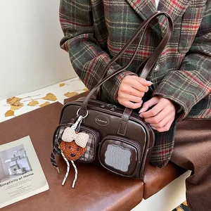 Detail der dunkelbraunen Vintage-Umhängetasche mit süßem Bärenanhänger und Markenlogo
