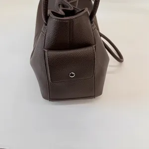 Detailed macro view of dark brown pebble leather side pocket with silver metal buckle
