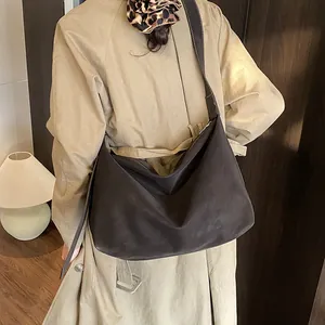 Detail of a large dark brown suede tote bag styled with a beige trench coat for autumn