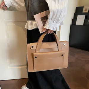 Detail of light brown leather laptop bag with double handles and metal snap flap pocket