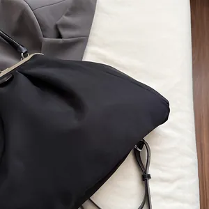 Close-up of black pleated cloud bag with vintage metal frame and slender shoulder strap