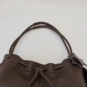 Detail of dark brown lychee textured leather tote bag with drawstring closure