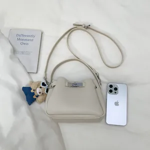 Detail of off-white lychee leather bucket bag with silver twist lock and bear charm