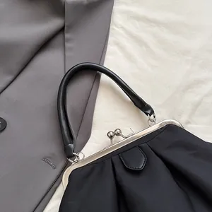 Detail of black pleated cloud handbag featuring silver retro metal clasp and round handle