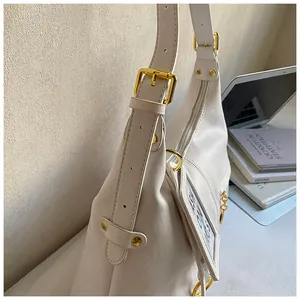 Detail of white large capacity hobo bag with adjustable gold buckles and strap