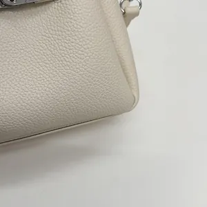 Detailed macro view of off-white lychee grain leather texture with silver metal hardware