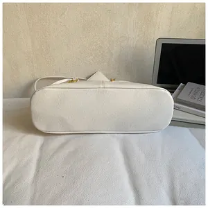 Detailed close-up showing the reinforced bottom stitching of a white leather shoulder bag
