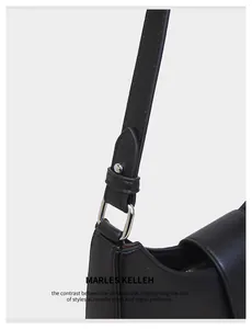Close-up of the silver metal D-ring buckle and premium black leather texture on the bag