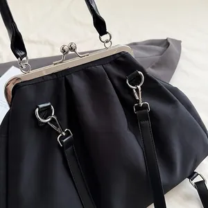 Detail of black pleated kiss-lock handbag with silver metal frame and dual straps