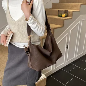 Detail of dark brown leather hobo bag with contrast white stitching and wide strap