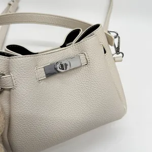 Close-up of beige lychee leather bucket bag with silver metal lock and contrast lining