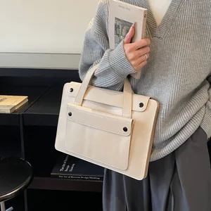 Detail of cream beige leather briefcase with minimalist outer pocket and black button