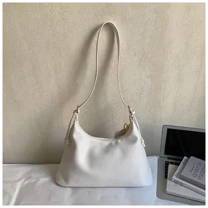 Detail of white leather shoulder bag with gold hardware and zipper in lifestyle setting
