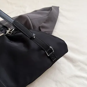 Detail of black nylon shoulder bag showing silver hardware and adjustable leather strap