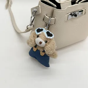 Detail of a plush poodle charm with sunglasses and overalls on a leather bucket bag