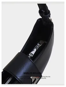 Detailed view of black litchi grain leather crescent bag with silver zipper closure