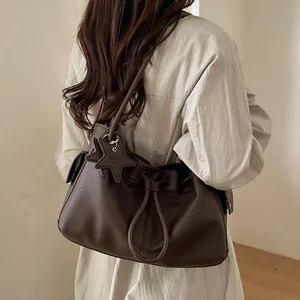 Detail of deep brown lychee texture tote bag with star pendant and drawstring closure