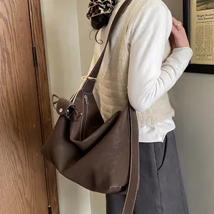 Detail of dark brown leather tote bag with white stitching and stylish shoulder strap