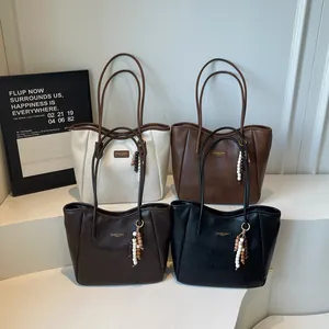 Detail view of large tote bags in four colors with beaded tassels and logo plates