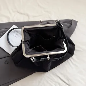 Close-up of the silver metal frame clasp and black interior lining of the pleated cloud bag