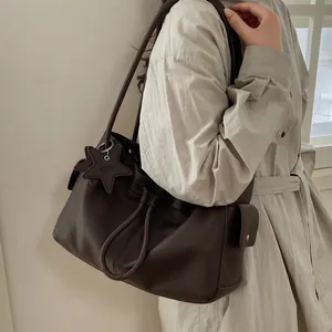 Close-up of deep brown lychee texture leather tote bag with star pendant and side pocket
