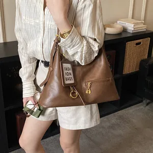 Detail of a dark brown retro hobo bag with gold hardware and a heart zipper pocket