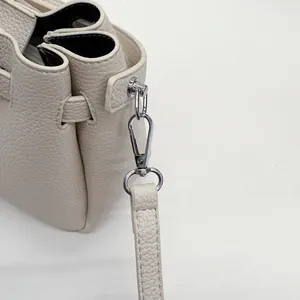 Detail of beige lychee pattern leather bucket bag showing silver hardware and stitching