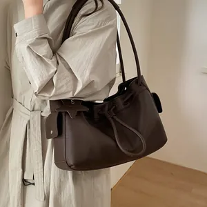 Detail view of coffee brown lychee grain shoulder bag with star charm and drawstring closure
