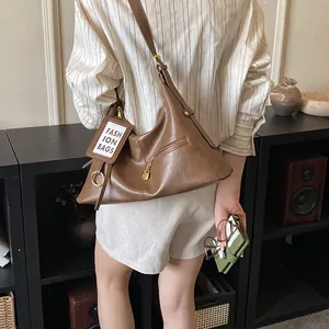 Detailed close-up of brown PU leather shoulder bag featuring gold chain and fashion tag