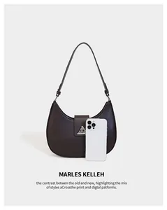 Detail view of a crescent hobo bag with phone for scale, featuring triangular metal hardware