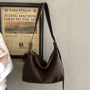 Detail view of large dark brown leather hobo bag with wide strap hanging on the wall