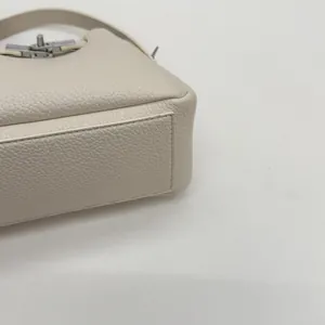 Detailed macro view of beige lychee grain leather with a silver swivel lock buckle
