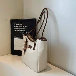 Detailed close-up of cream tote bag featuring contrast brown straps and beaded charm