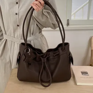 Close-up of deep brown lychee grain leather tote bag with drawstring and star charm