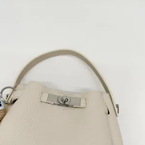 Close-up of beige bucket bag featuring silver twist lock and lychee leather texture