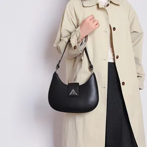 Detail of minimalist black hobo bag with silver triangle clasp on beige trench coat