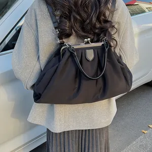 Rear view of a stylish black pleated cloud bag worn as a backpack in an outdoor setting
