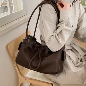 Close-up of deep brown lychee grain leather tote with star charm and drawstring detail