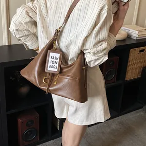 Detail of dark brown leather hobo bag featuring metal ring and fashion tag hanging