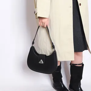 Detail view of a black crescent hobo bag with a silver triangular buckle on an elegant model