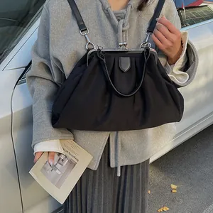 Detail of a black pleated cloud bag with silver metal frame worn on a model's shoulder