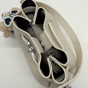 Detail of cream bucket bag with drawstring closure, silver twist lock and bear charm