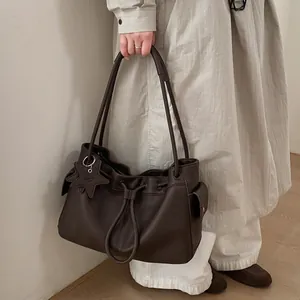 Detail of coffee brown lychee pattern leather tote bag with star charm and drawstring